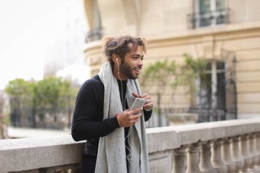 Melez adam akıllı telefon ve kulaklık Eyfel Kulesi ile zevk