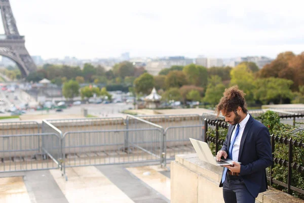 Mixed blood businessman working with laptop near Eiffel Tower in