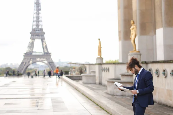 Mulat pressman lezen krantenartikel in de buurt van Eiffel Tower. — Stockfoto