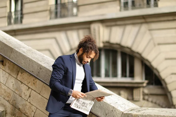 Young male model reading newspaper on open air.