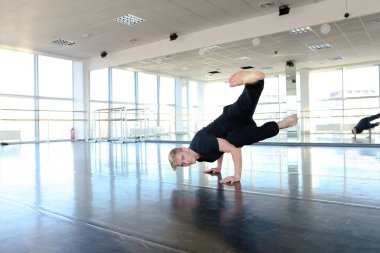 Sicim üzerinde oturan ve germe yapıyor genç dansçı.