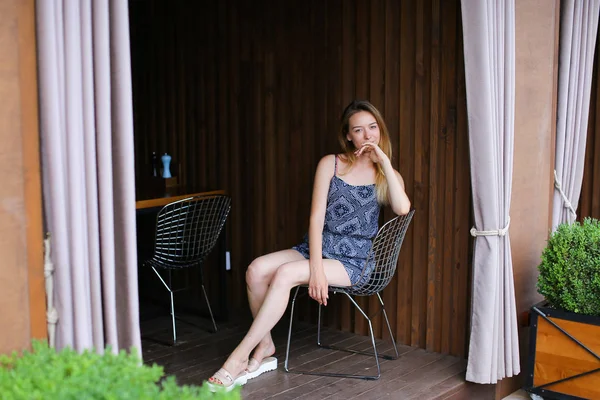 Jonge vrouw kijken camera en lachend in de buurt van café met close — Stockfoto