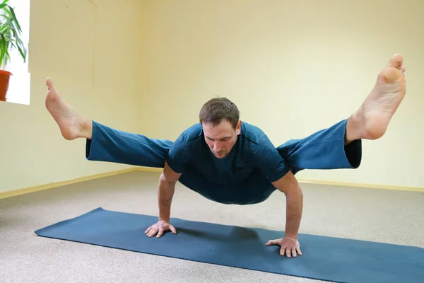 Man of European appearance sits on floor and performs cross twin — Stock Photo, Image