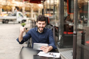 Hoşnutsuz adam online oyun tarafından tablet sokak café'de oynuyor..