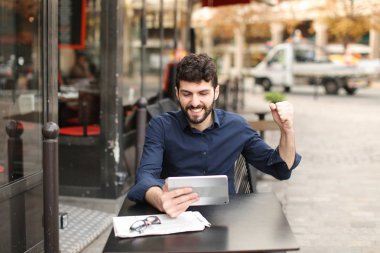 Hoşnutsuz adam online oyun tarafından tablet sokak café'de oynuyor..