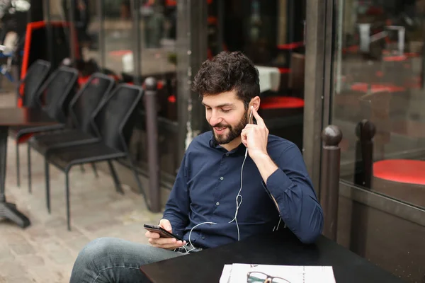 Student listening to music with smartphone and earphones at cafe