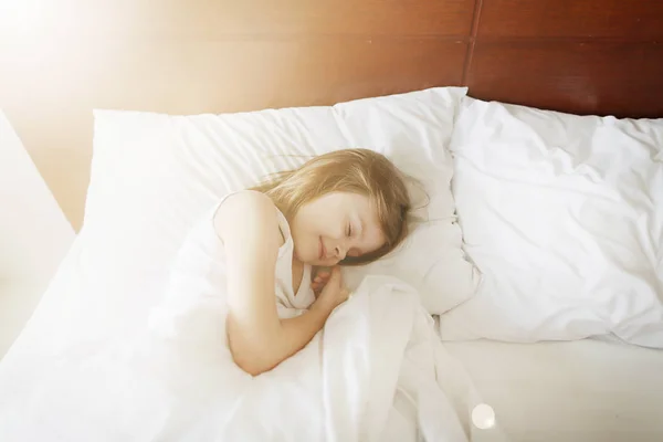 Солнечный портрет спящей девочки у белой кровати — стоковое фото