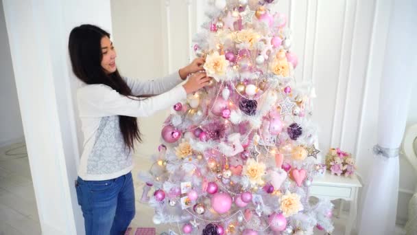 Mujeres guapas en buenos espíritus decoradas con un árbol de Navidad festivo, mirando a la cámara y sonriendo en el dormitorio blanco . — Vídeo de stock