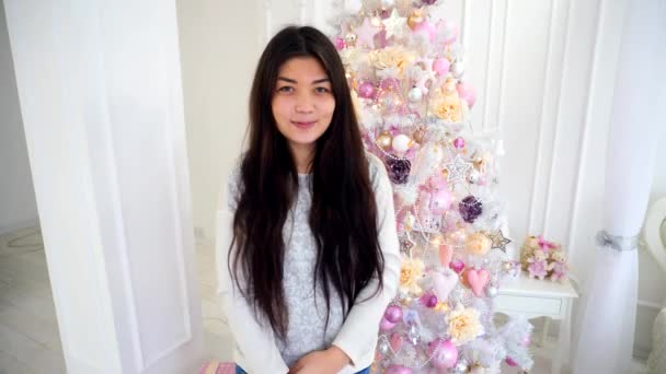 Alluring Girl in Anticipation of New Year Celebrations Smiling at Camera on Background Decorated Christmas Tree in White Room. — Stock Video