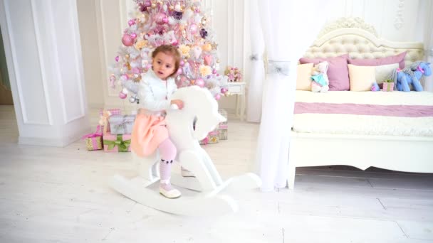 Niña jugando en la habitación de los niños sobre fondo rosa árbol de Navidad con juguetes . — Vídeos de Stock