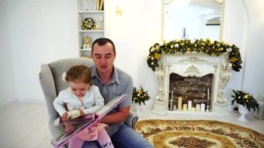 Neşeli küçük kız ve baba eğlenceli ve o gülmek ve gülümsemek etrafında aptal Festively arka planda büyük parlak odada sahip şömine dekore edilmiş.