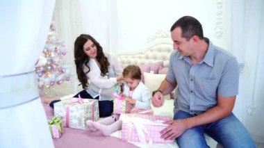 Dostu aile şenlikli ruh parlak oda şenlikli Noel ağacı arka plan üzerinde oturup hediyeleri.