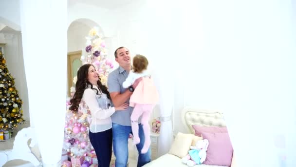 Familia alegre divirtiéndose y riendo en la luz espaciosa del dormitorio en el fondo del árbol de vacaciones y la cama grande . — Vídeo de stock