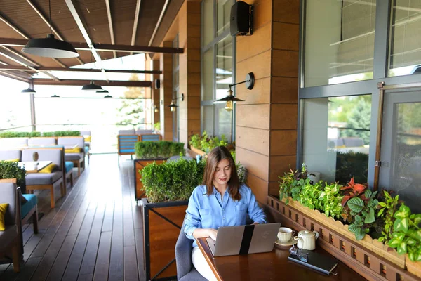 Estudiante charlando por ordenador portátil con amigos en la cafetería . — Foto de Stock