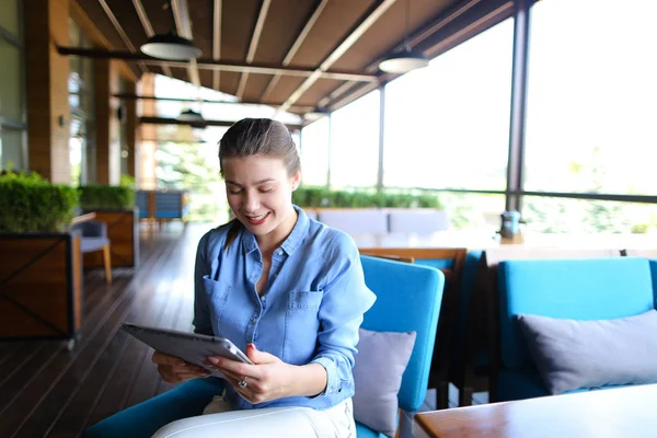 Chica alegre trabajando con la tableta en la mesa del restaurante . — Foto de Stock