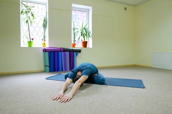 Stilig man sitter på golvet på matta för yoga i lotusställning — Stockfoto