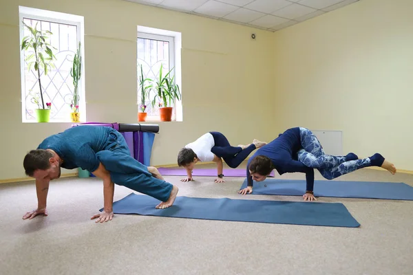 Young woman yoga trainer teaches the boy and girl to do the exer