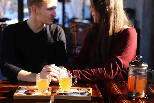 Couple sitting near table with sea-buckthorn broth in cafe discu