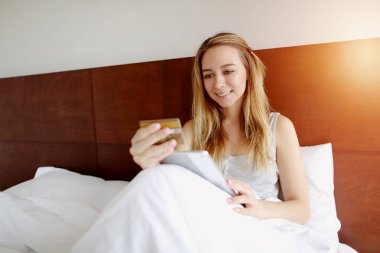 mal online satın alma kadın mutlu ile banka kredi kartı ve yatakta beyaz evde güneş ışığı ile döşeme tablet