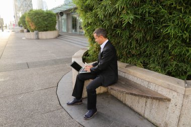 İşadamı çevre bitki dışarıda dizüstü bilgisayar ile çalışma  .