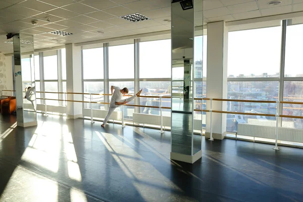 Ginasta no treinamento de sportswear perto do balé barre no ginásio esporte — Fotografia de Stock