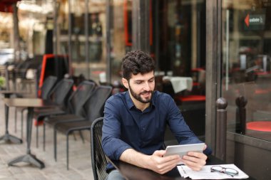 Hoşnutsuz adam online oyun tarafından tablet sokak café'de oynuyor..