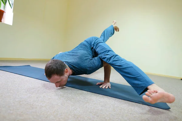 Man of European appearance sits on floor and performs cross twin — Stock Photo, Image