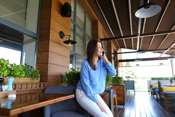 Chica joven hablando por teléfono inteligente en el restaurante   . — Foto de Stock
