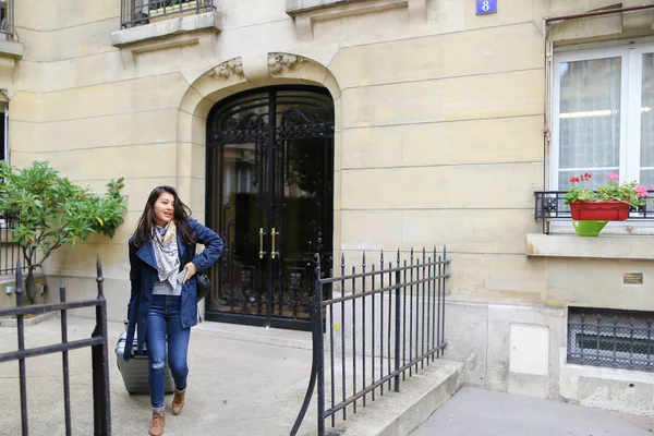 Chinese girl leaving university building with valise and talking