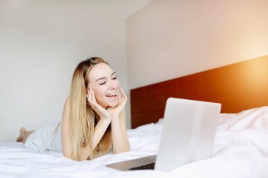 sevimli kadın mutlu beyaz yatak uzaktan evde film izlerken laptop ile portresi