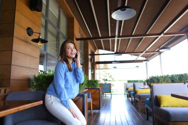 Genç kız yanında smartphone restoranda konuşuyor  .