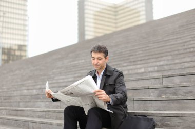 merdivenlerde oturan ve gazete okuyan erkek iş öğretmen