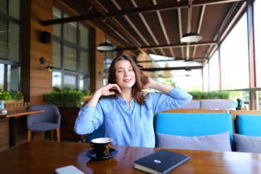 Rüzgarlı havanın tadını ve kafede saçlı oynayan genç kız