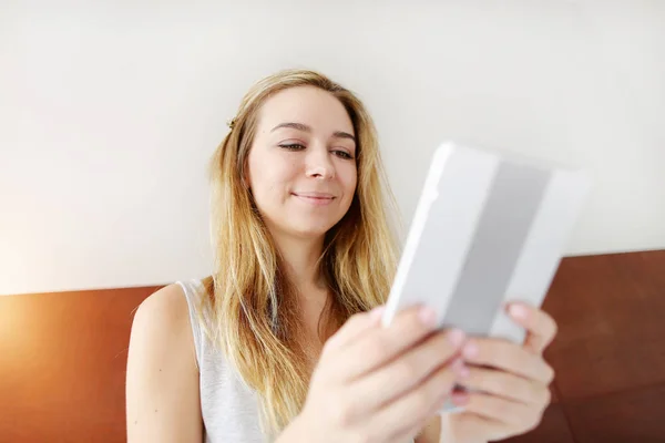 Молода жінка працює щаслива з планшетом на білому ліжку — стокове фото