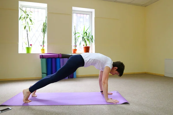 Hermosa joven con cabello oscuro realiza ejercicios de yoga . —  Fotos de Stock