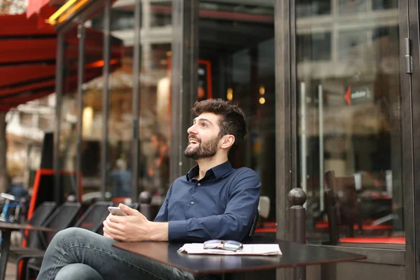 American boy listening to music at cafe with earphones and smart