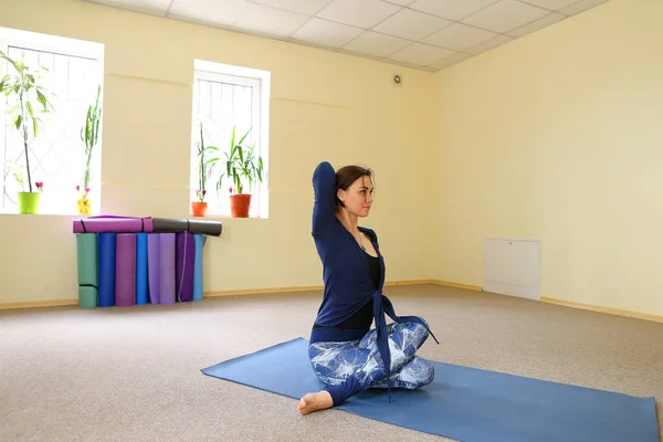 Chica europea de pelo oscuro haciendo calentamiento en la sala de fitness espaciosa — Foto de Stock