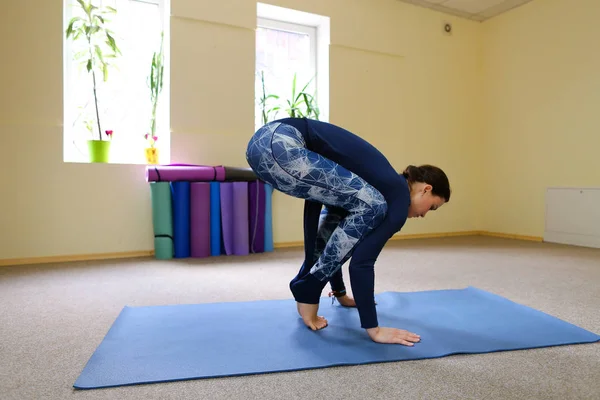 Chica europea de pelo oscuro haciendo calentamiento en la sala de fitness espaciosa — Foto de Stock