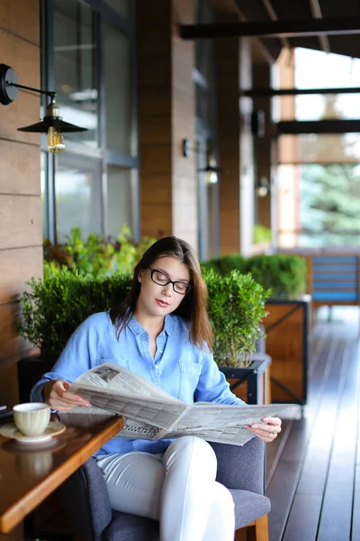 若い女性の新聞を読むと、レストランでスマート フォンを使用して — ストック写真