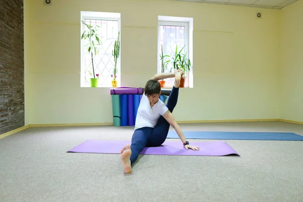 Chica europea de pelo oscuro haciendo calentamiento en la sala de fitness espaciosa — Foto de Stock