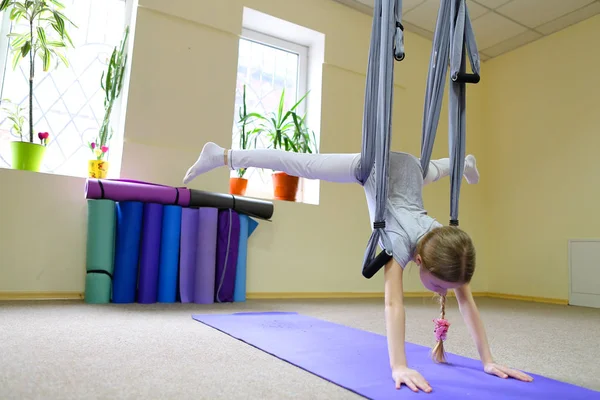 Schoolgirl sits on twine on acrobatic ropes.