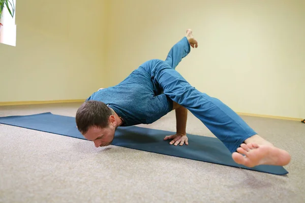 Man of European appearance sits on floor and performs cross twin — Stock Photo, Image