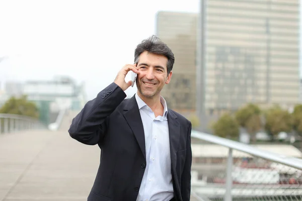 European businessman walking and speaking by telephone.