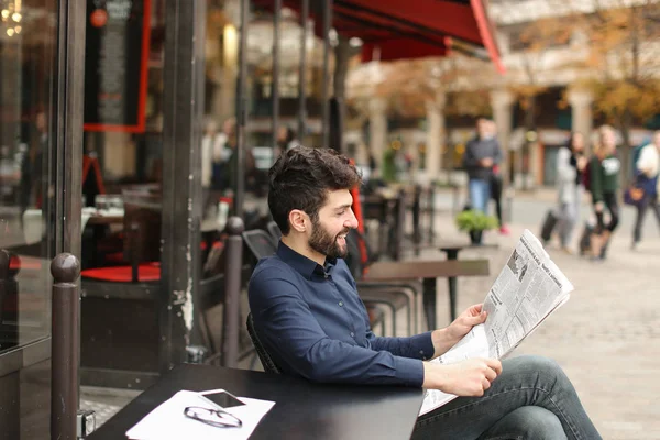 Journalist with close up face reading newspaper article at cafe