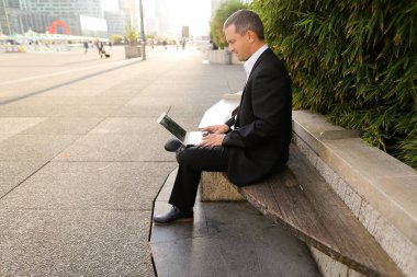 İşadamı çevre bitki dışarıda dizüstü bilgisayar ile çalışma  .