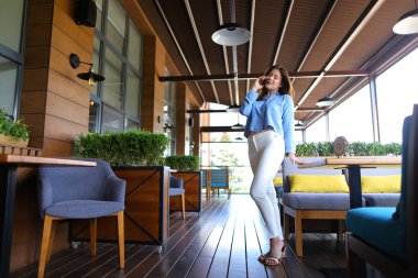 Kol sandalyede oturan ve smartphone vasıl tarafından konuşmak güzel kız