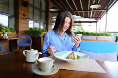 Kafede oturan, smartphone tarafından sohbet ve sahip güzel kadın