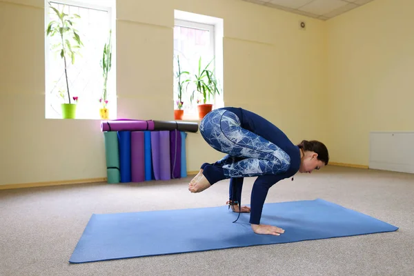 Chica europea de pelo oscuro haciendo calentamiento en la sala de fitness espaciosa — Foto de Stock