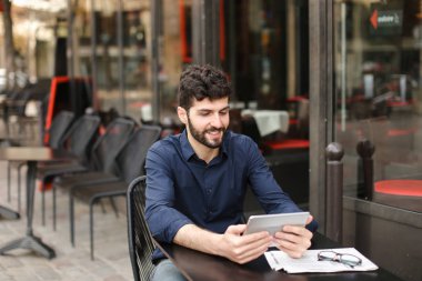 Hoşnutsuz adam online oyun tarafından tablet sokak café'de oynuyor..