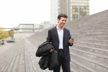 fotoğrafları izlemek için Smartphone kullanarak yürüyüş iş adamı.